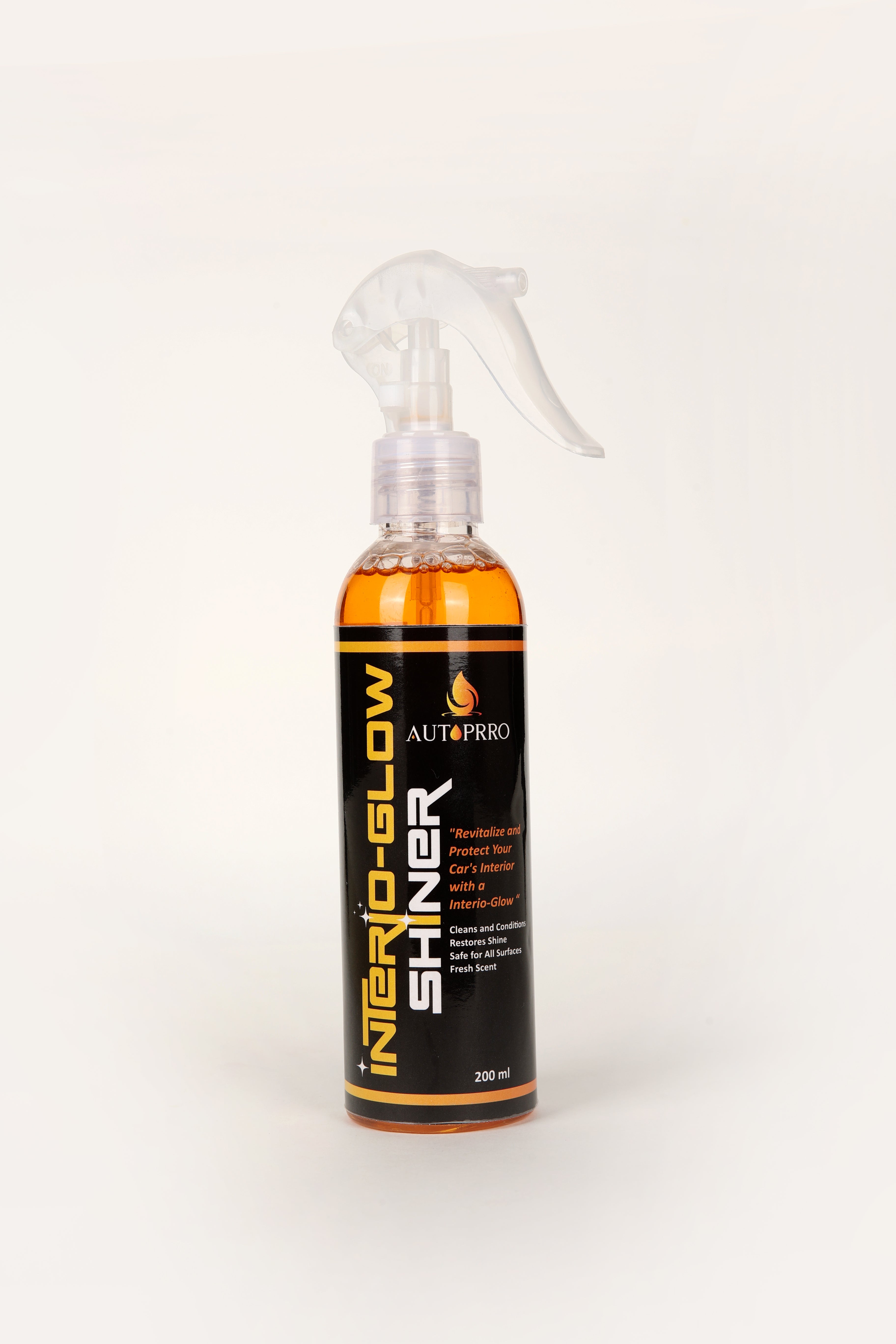 A spray bottle of Autoprro Interio-Glow Shiner with orange liquid visible through the transparent spray nozzle.